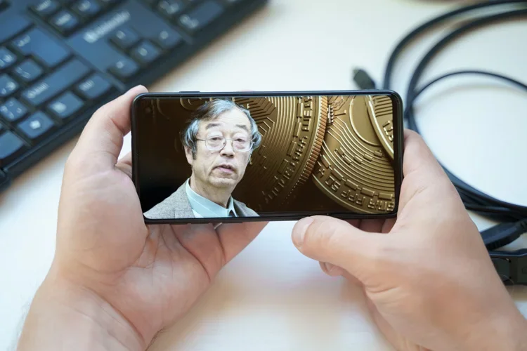 Сатоши Накамото на фоне биткоина смотрит со смартфона.