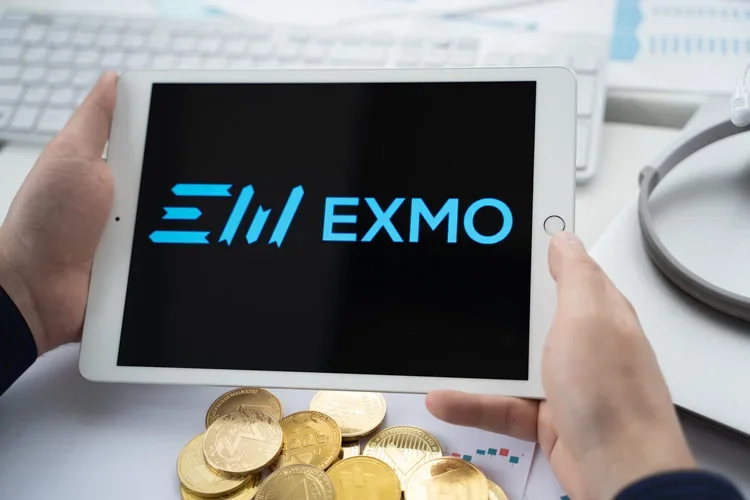 Логотип EXMO открыт на черном фоне на экране IPad.