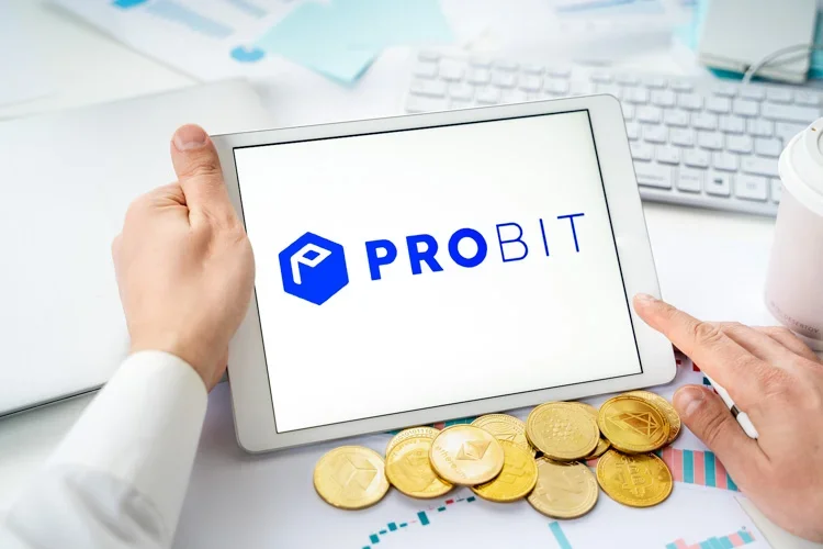 Криптовалютная биржа ProBit открыта на экране смартфона, а снизу лежат монетки криптовалют.