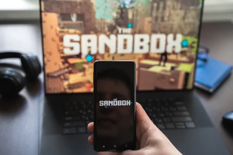 Блокчейн-игра The Sandbox открыта на экране смартфона и ноутбука.