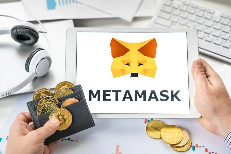 MetaMask открыт на мониторе, а в руках кошелек с монетками криптовалют.
